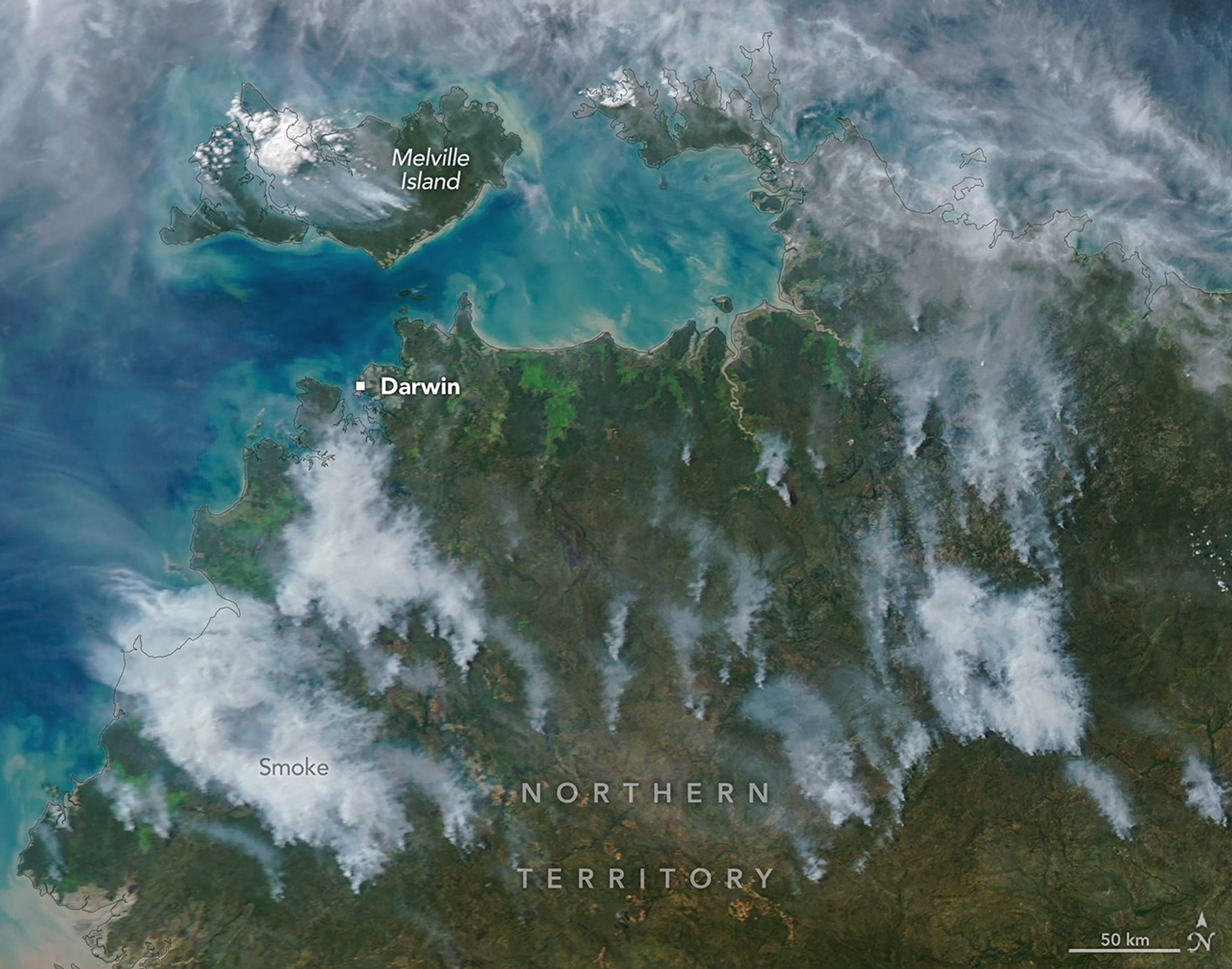 Several gray smoke plumes are visible drifting over a green landscape.