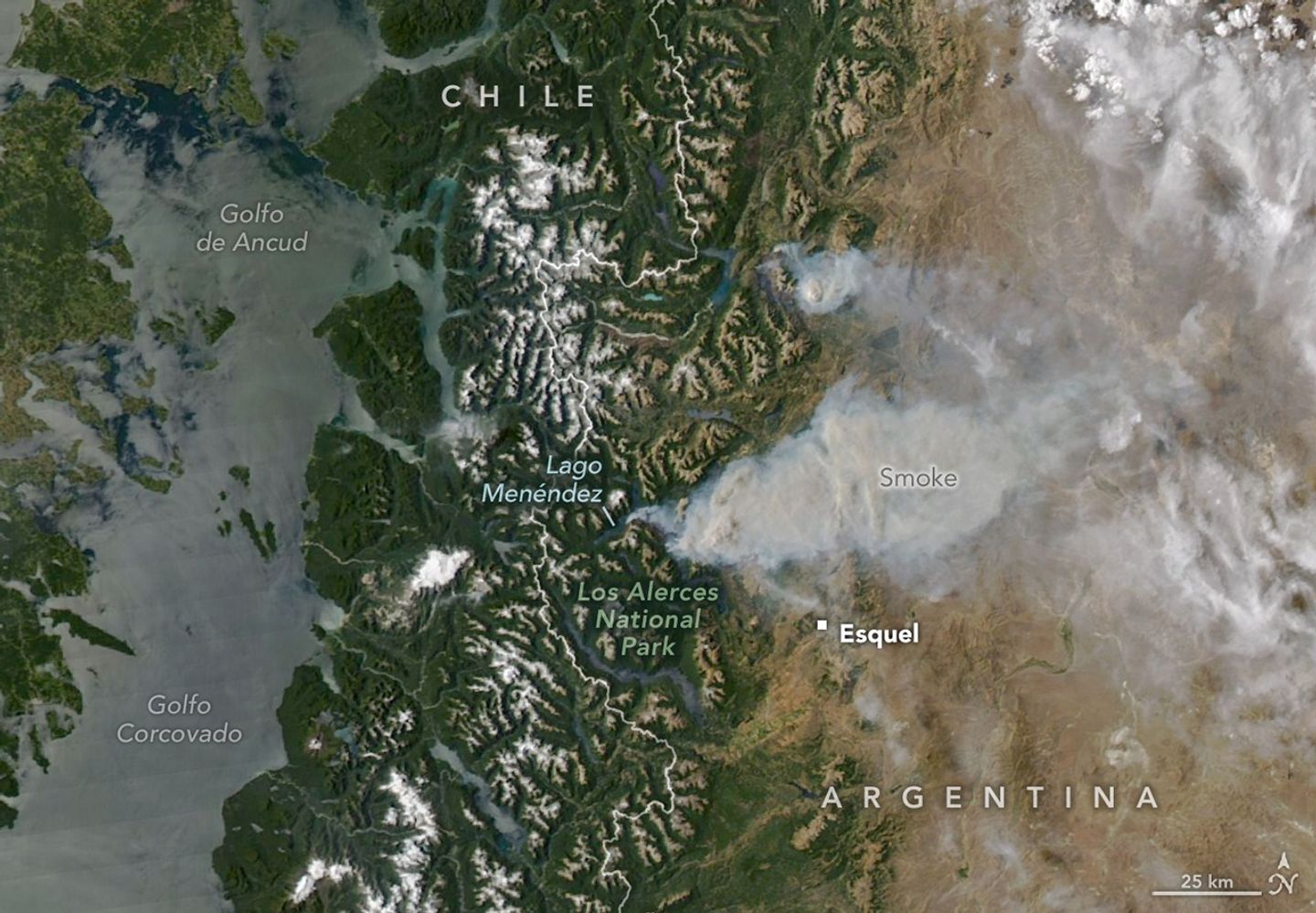 Two thick plumes of gray wildfire smoke spread from Patagonia's forested, snow-capped mountains in the middle of the scene into Argentina's brown, drier plains to the right.