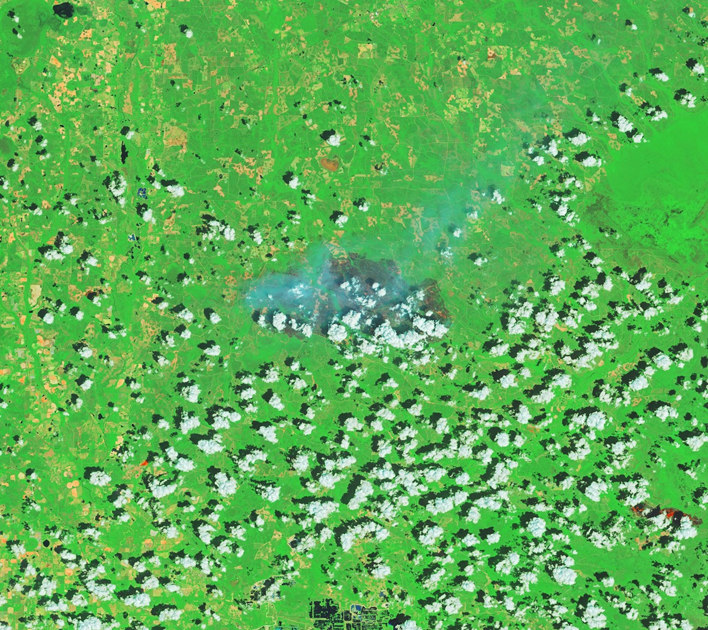 A patch of burned area near Fruitland appears gray amid a background of green vegetation. Small scattered clouds are visible in the lower part of the image.