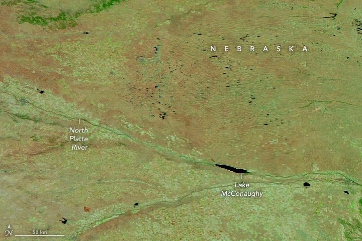 Plains in western Nebraska, divided by the North Platte River, appear in light shades of green and brown in a false-color satellite image.
