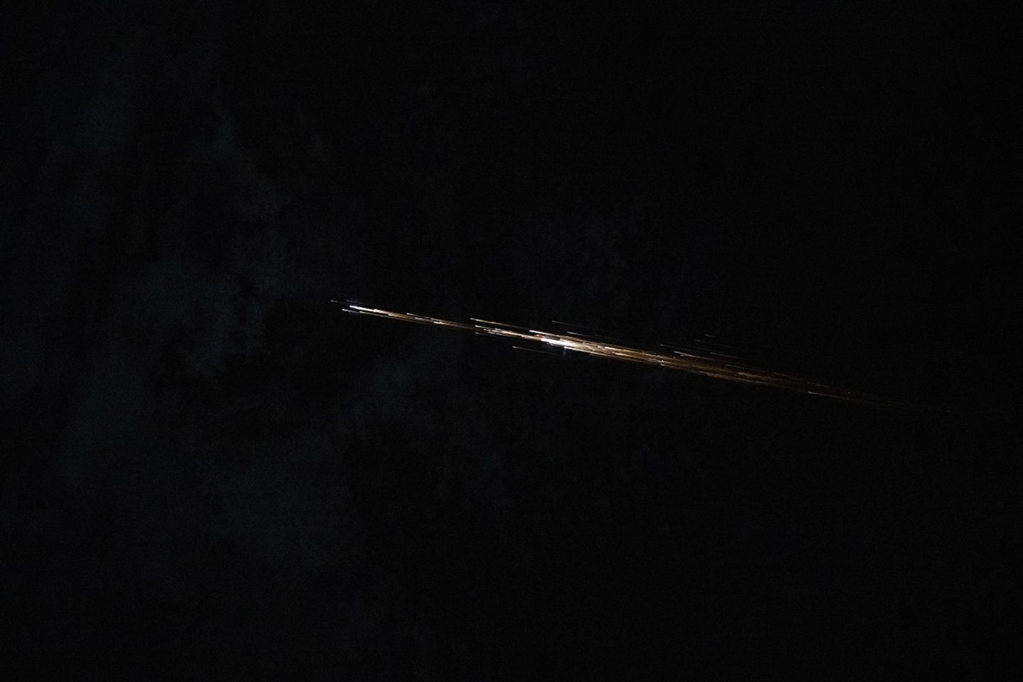 Several long streaks of light are clustered in a line pattern as they streak across a dark background.