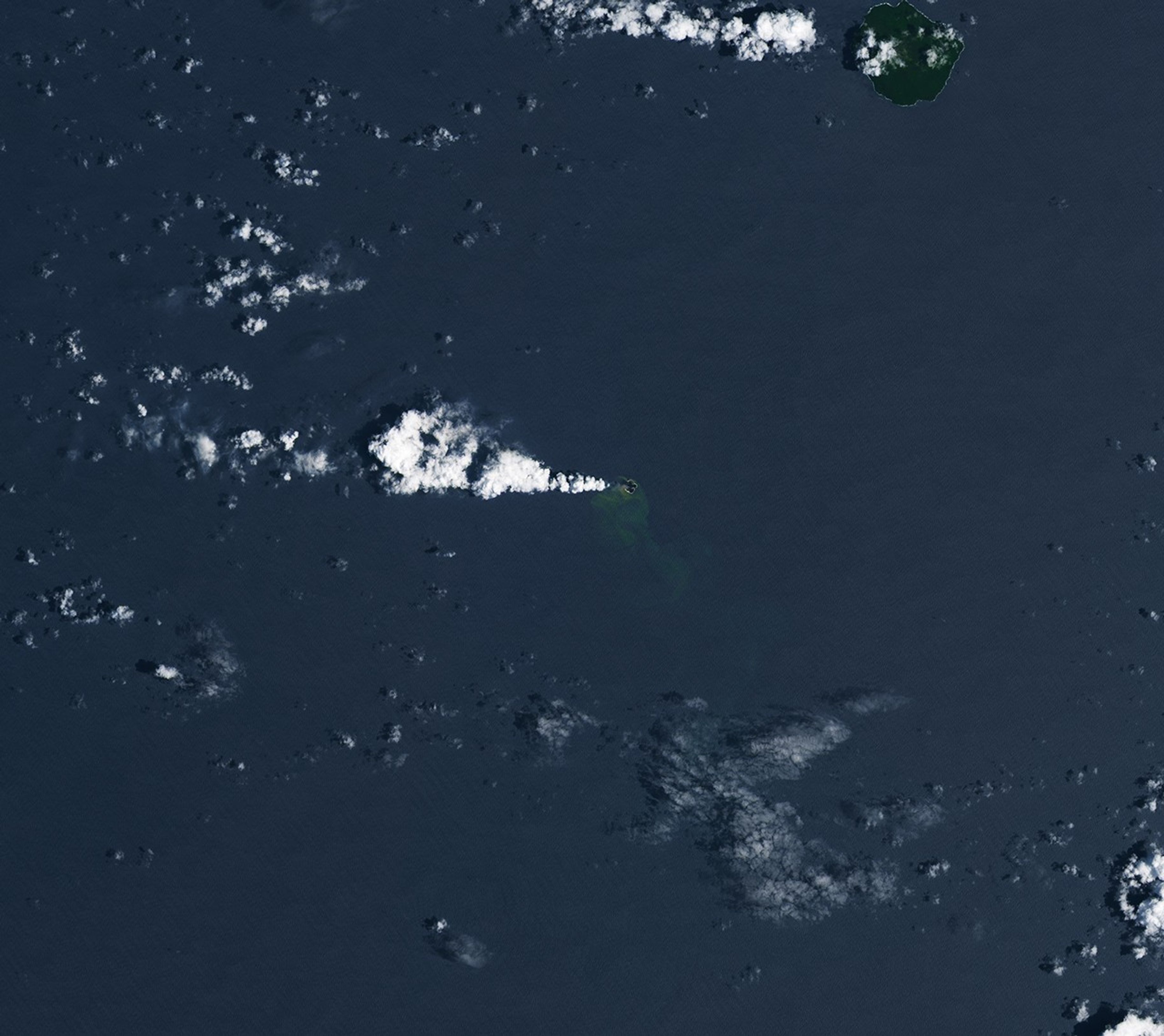 Three panels show the small volcanic island of Home Reef on different dates in December 2025 and January 2026. In each image from left to right, the island appears slightly larger, and plumes of volcanic gases and greenish, discolored water are more pronounced.