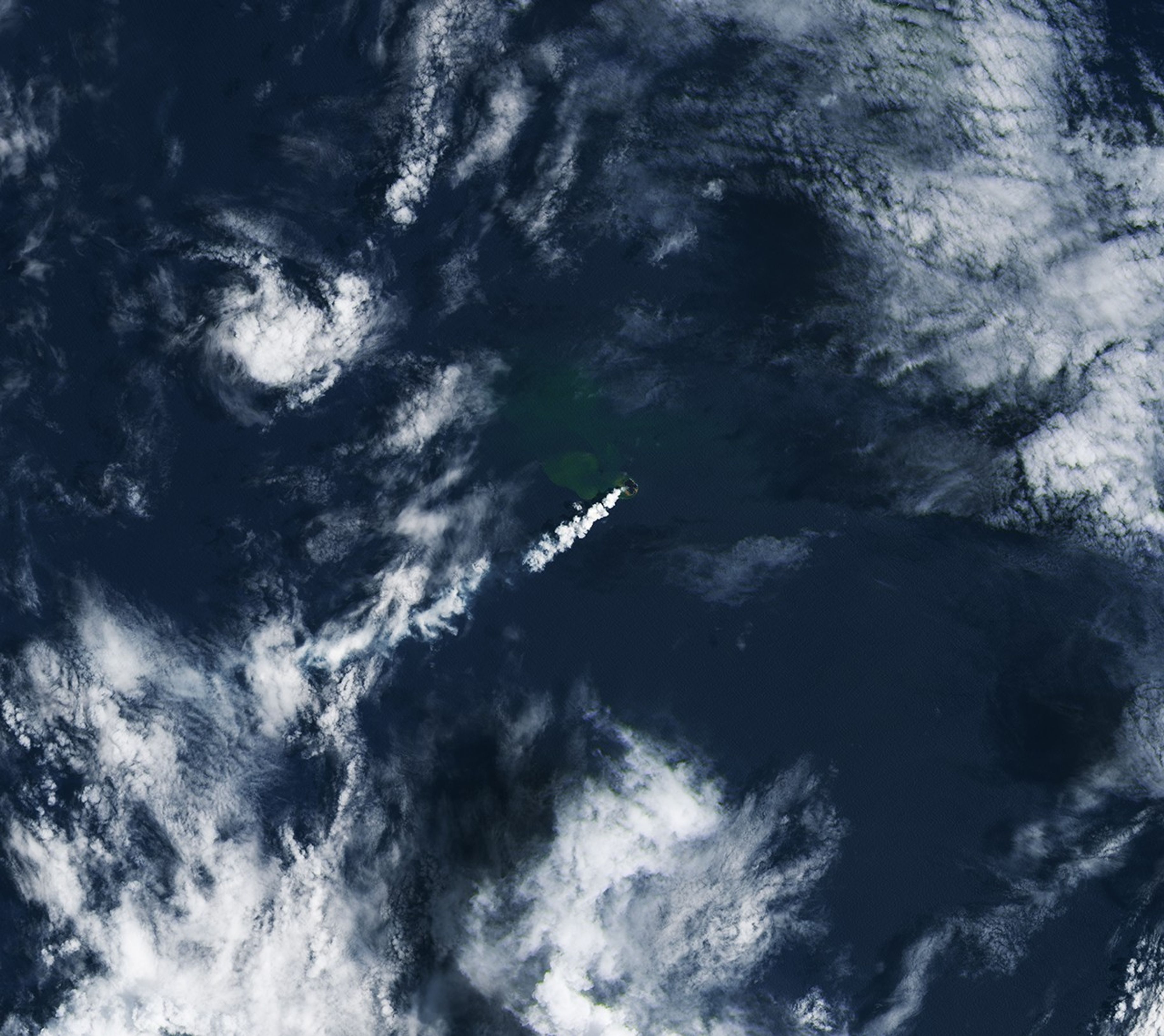 Three panels show the small volcanic island of Home Reef on different dates in December 2025 and January 2026. In each image from left to right, the island appears slightly larger, and plumes of volcanic gases and greenish, discolored water are more pronounced.