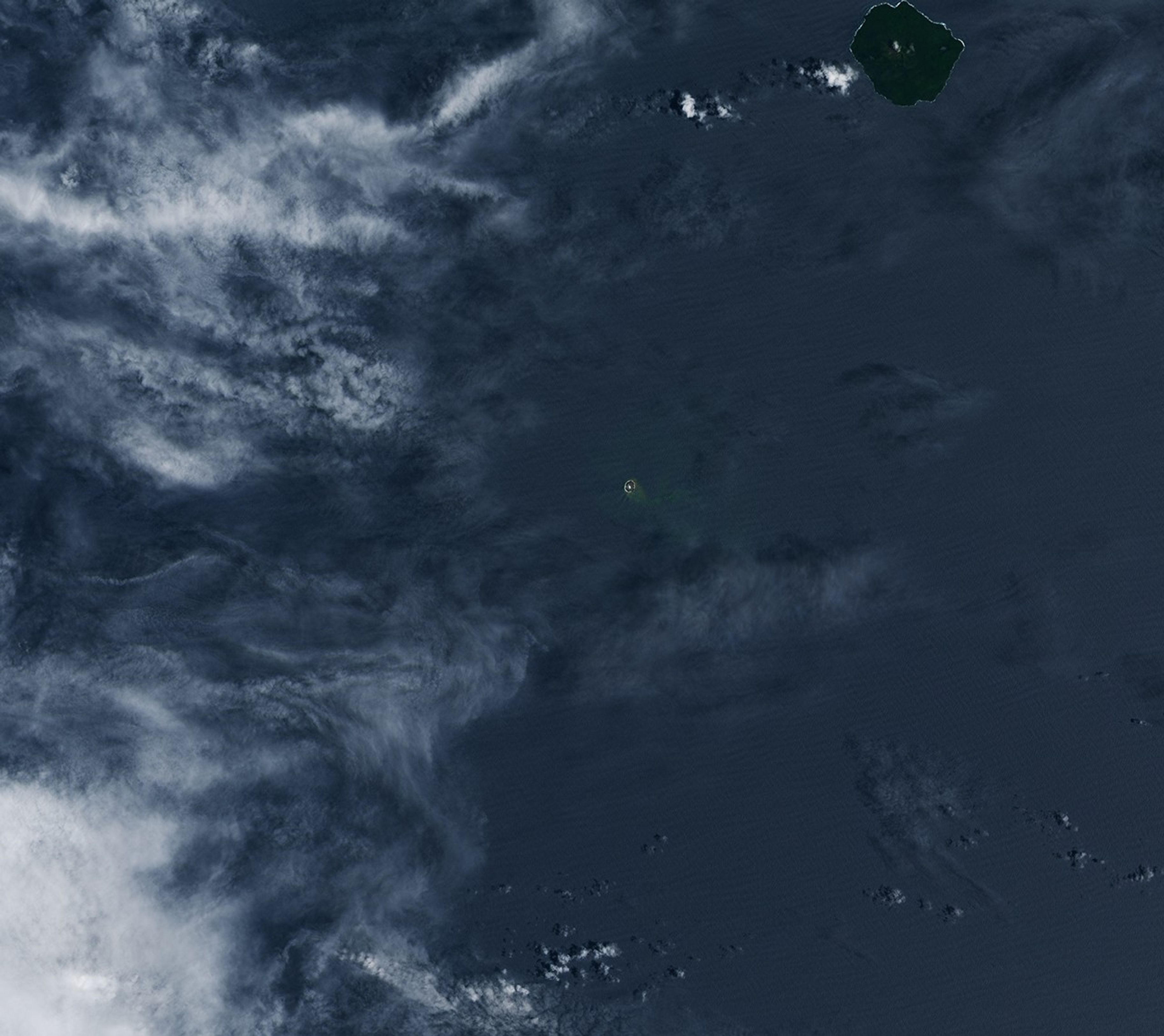 Three panels show the small volcanic island of Home Reef on different dates in December 2025 and January 2026. In each image from left to right, the island appears slightly larger, and plumes of volcanic gases and greenish, discolored water are more pronounced.