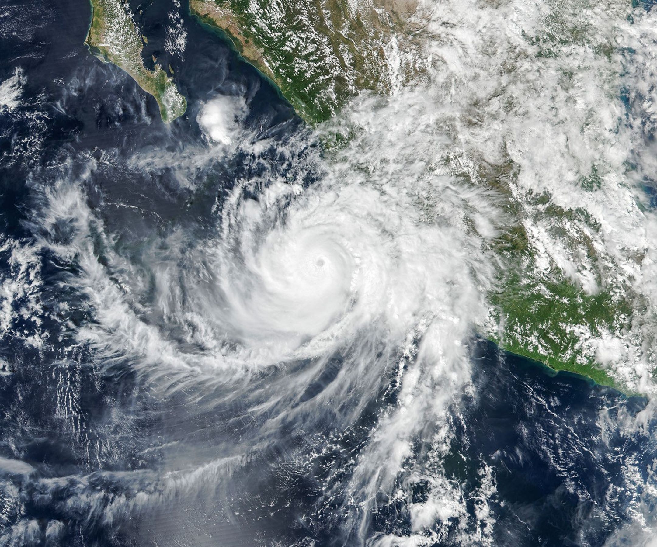 The well-defined eye of Hurricane Simon lies just off Mexico’s Pacific coast. Some outer cloud bands of the spiraling storm extend over land.