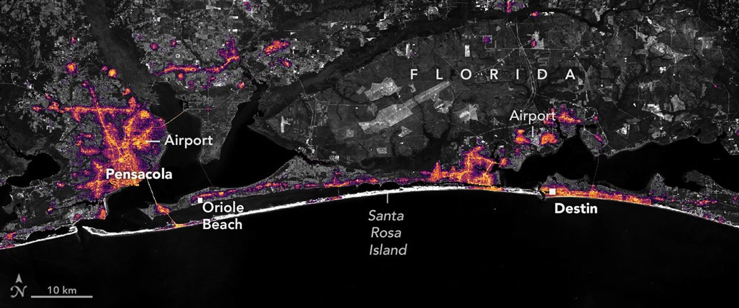 Nighttime lights along the Florida Panhandle coast in August 2026, brightest in Pensacola and Destin and along the road between them.