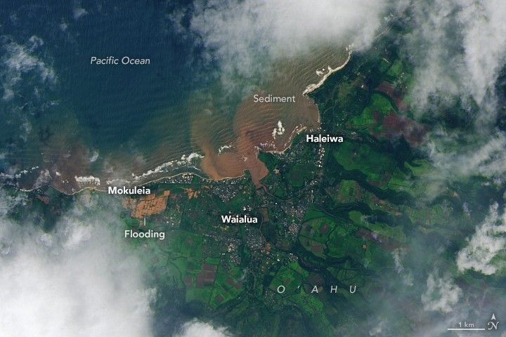The same area, with brown floodwater pooling across farmland between Mokuleia and Waialua, with a red-brown plume spreading into the coastal ocean.