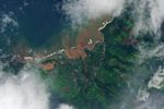 The same area, with brown floodwater pooling across farmland between Mokuleia and Waialua, with a red-brown plume spreading into the coastal ocean.