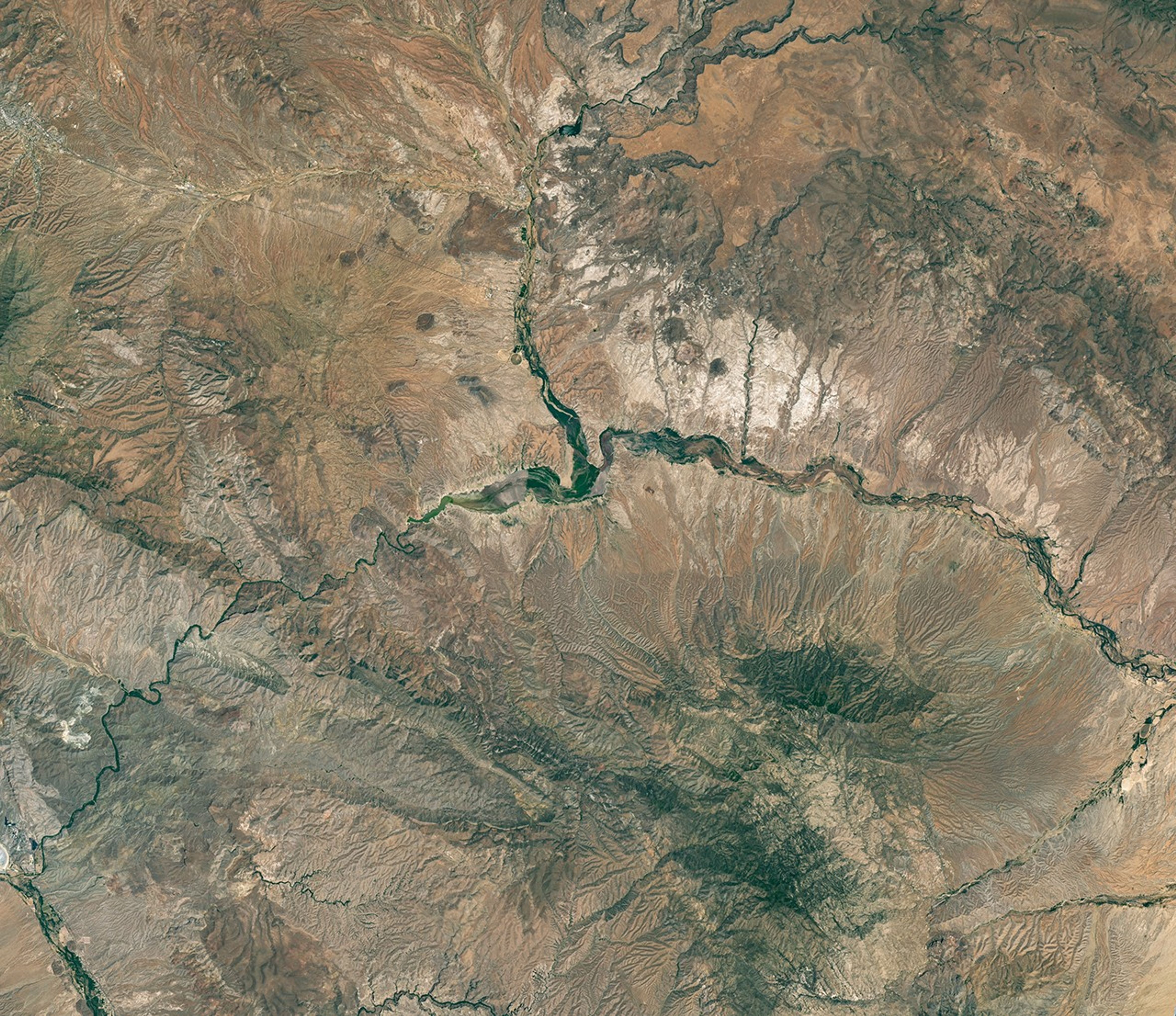 The reservoir is nearly empty by May 2026. The Gila River's natural channel is now visible and flanked with green vegetation in what had been the bottom of the reservoir.
