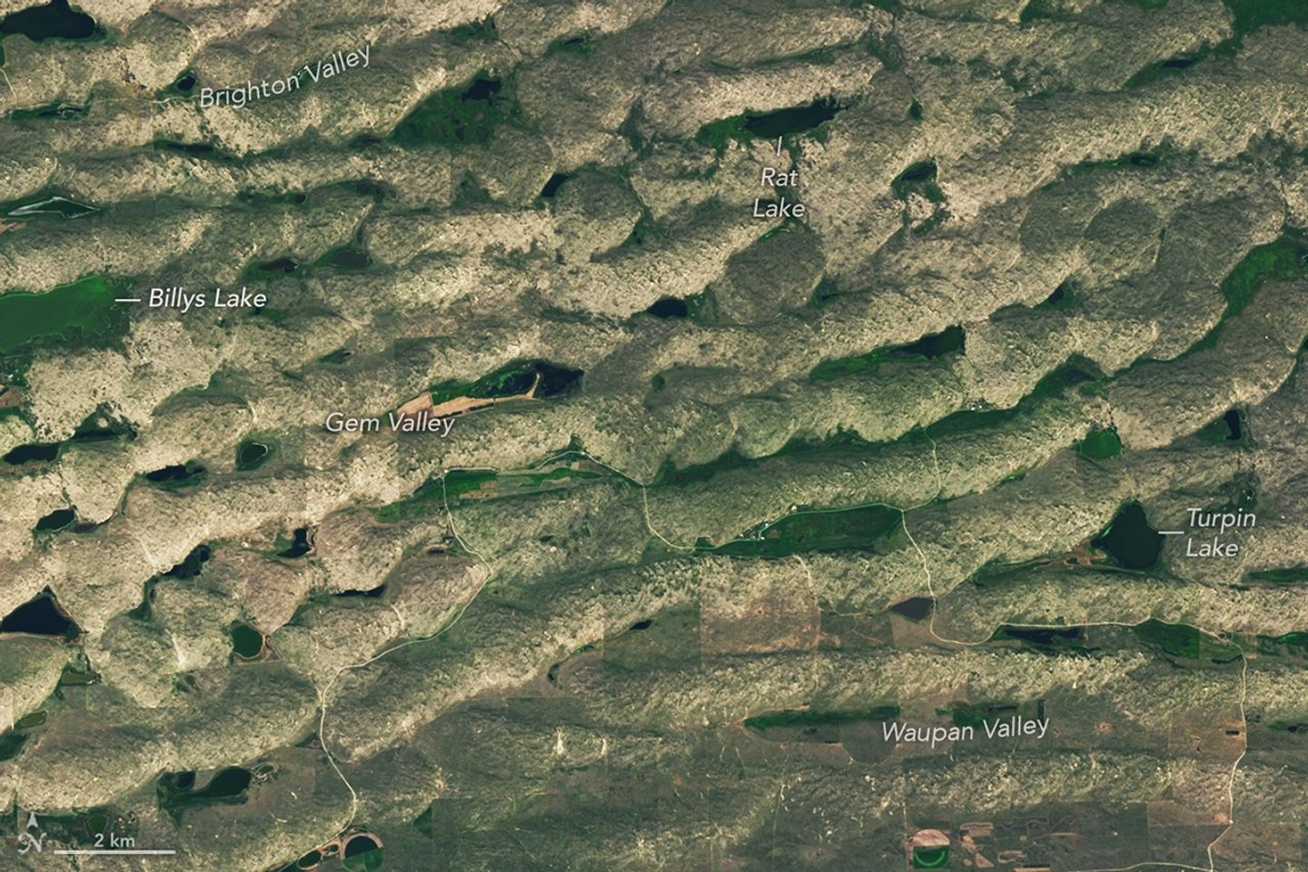 A series of tan parallel ridges runs from left to right, with green areas and small lakes filling the low-lying spaces in between.