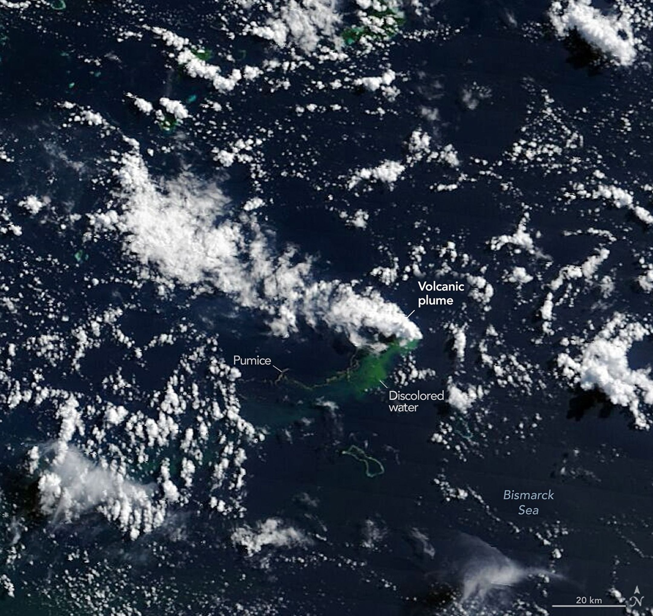 A long gray line extends west and joins with a patch of discolored green water and a cloud-like volcanic plume near the center of the image.