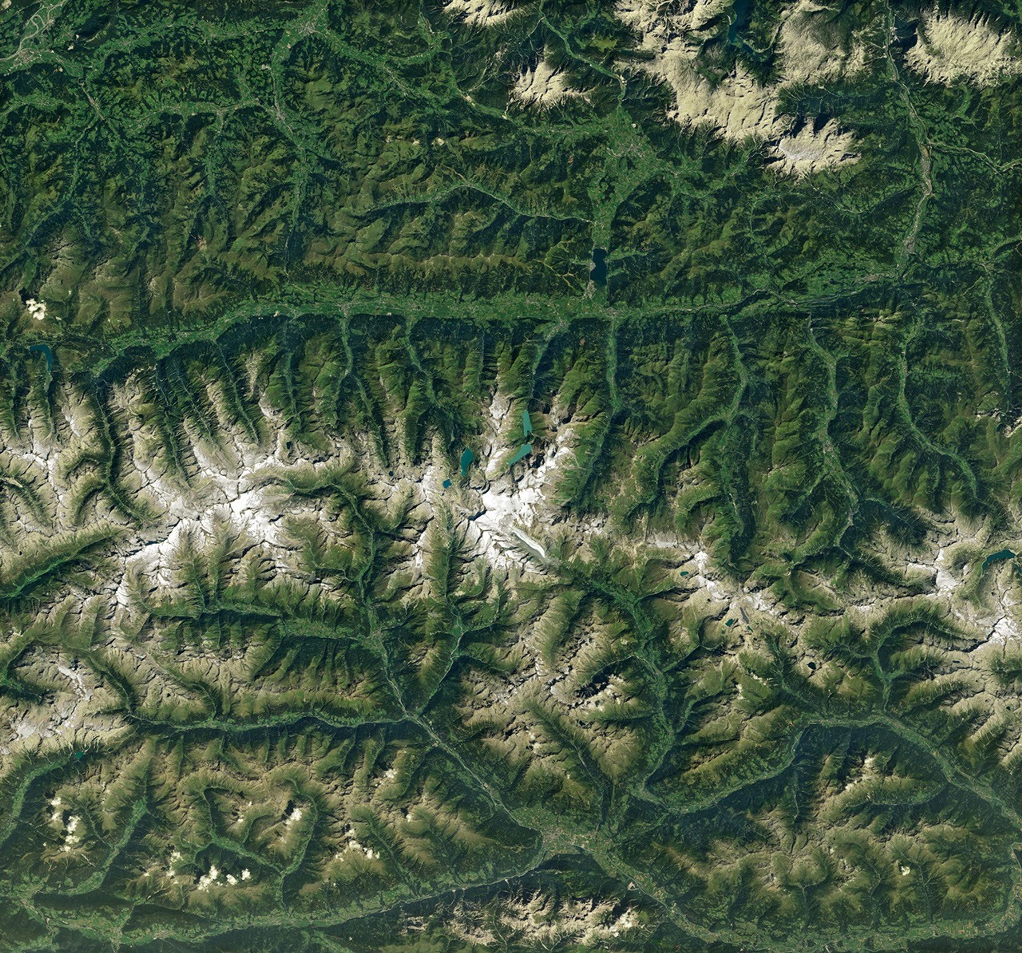 Ice in a broad Alpine basin feeds debris-covered glacial ice several kilometers long in the valley below.