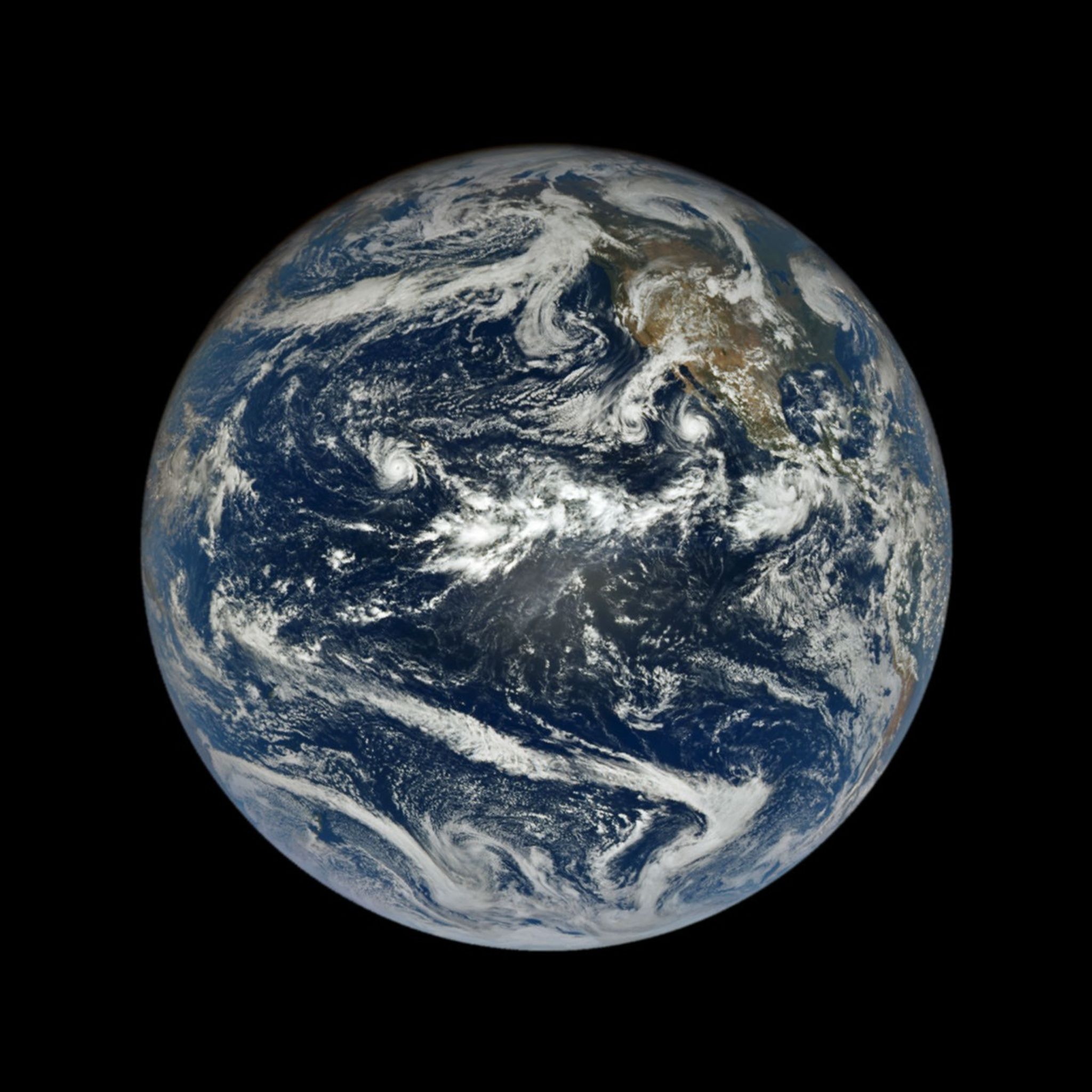 In a full-disk satellite view of Earth, several tropical cyclones swirl above the blue waters of the Pacific Ocean.