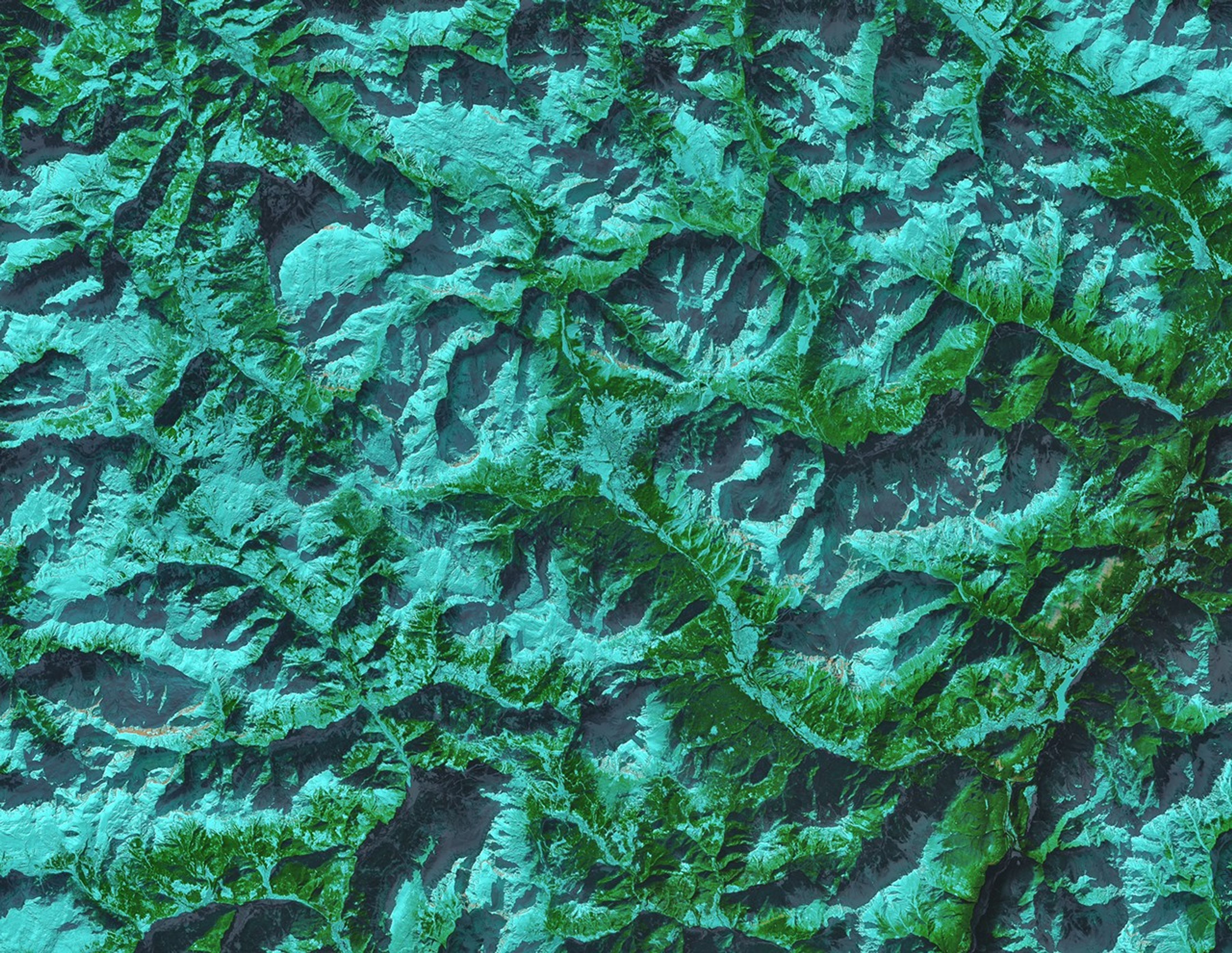 A false-color satellite image shows the town of Cortina d’Ampezzo, Italy, surrounded by tall mountains in the Dolomites. Snow appears light blue, forested areas are green, and bare cliff bands and light brown.