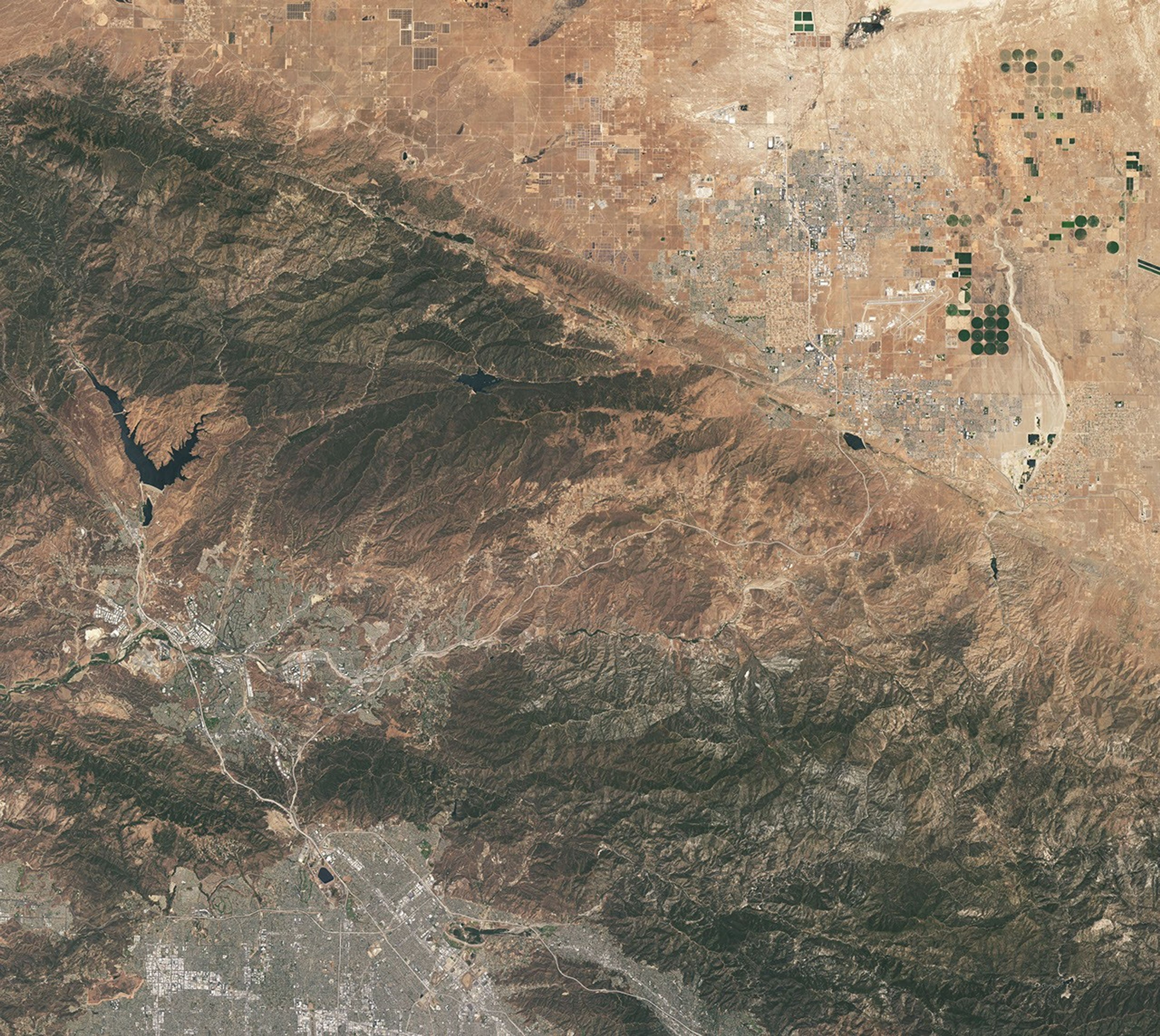 This natural-color image shows the same area, but there is less difference in colors between higher-elevation and lower-elevation vegetation. Most features in the image are shades of brown.
