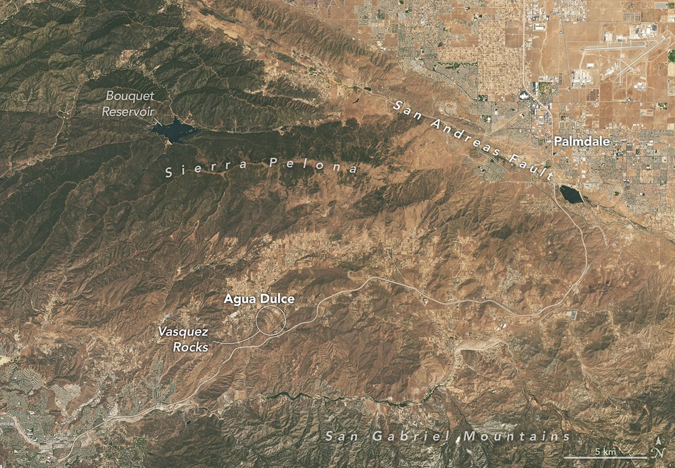 This natural-color image shows the same area, but there is less difference in colors between higher-elevation and lower-elevation vegetation. Most features in the image are shades of brown.