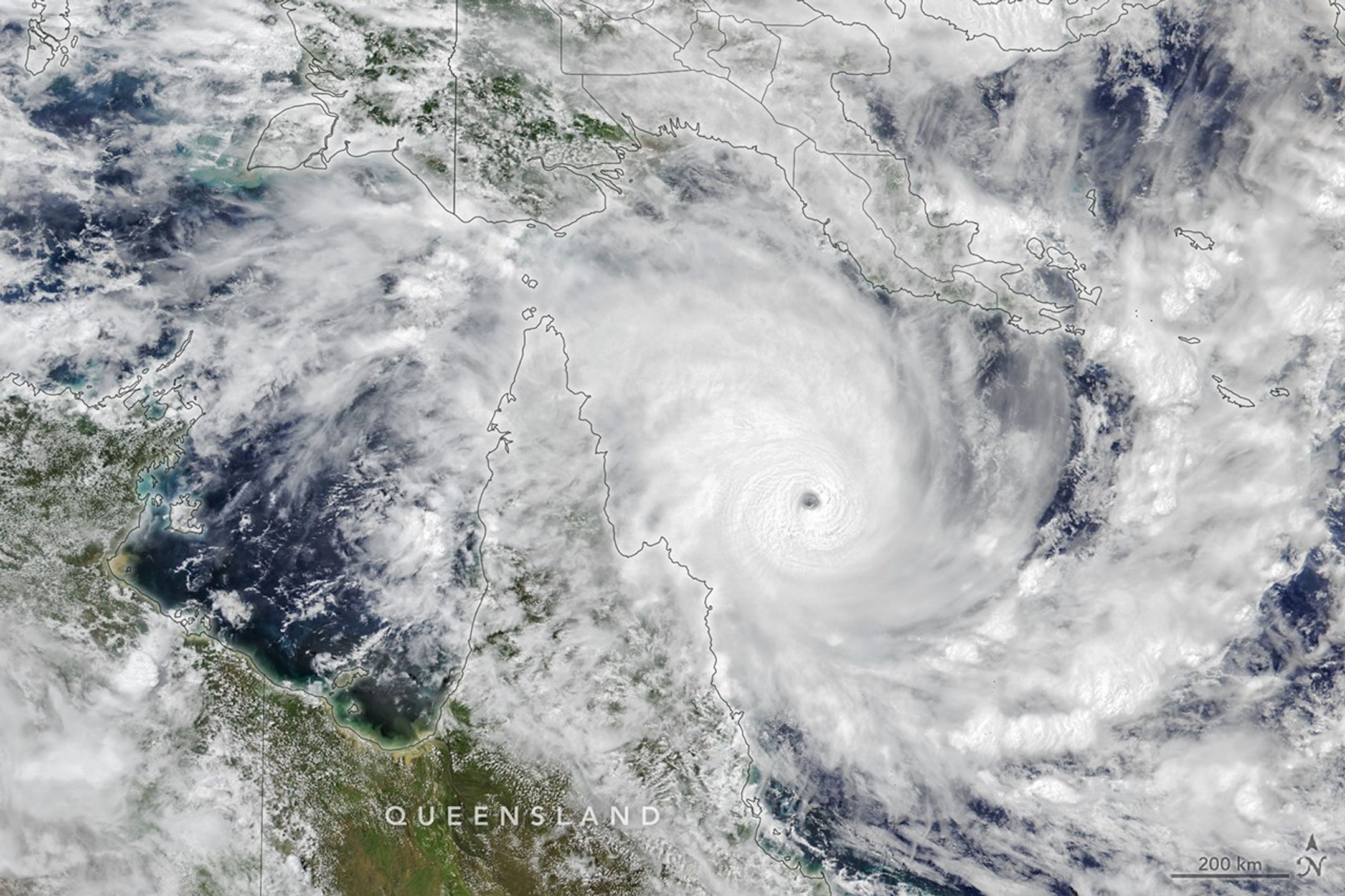 A tropical cyclone with spiraling clouds and a well-defined eye sits off the coast of Queensland, Australia.