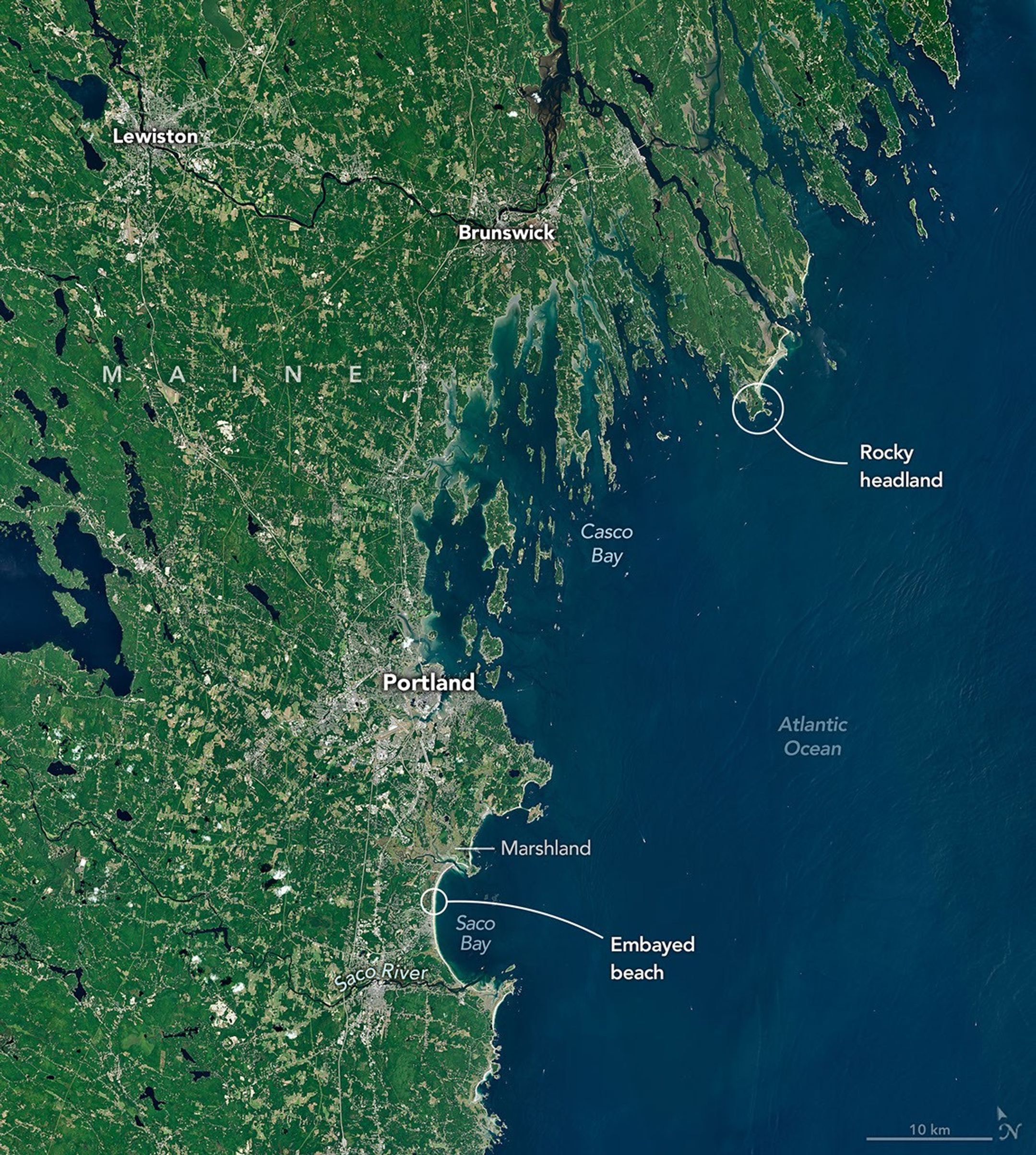 A satellite image of the Maine coastline highlights smooth, sandy beaches near Saco Bay on the left and the rocky, jagged coastal features near Casco Bay on the right.