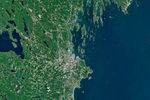 A satellite image of the Maine coastline highlights smooth, sandy beaches near Saco Bay on the left and the rocky, jagged coastal features near Casco Bay on the right.