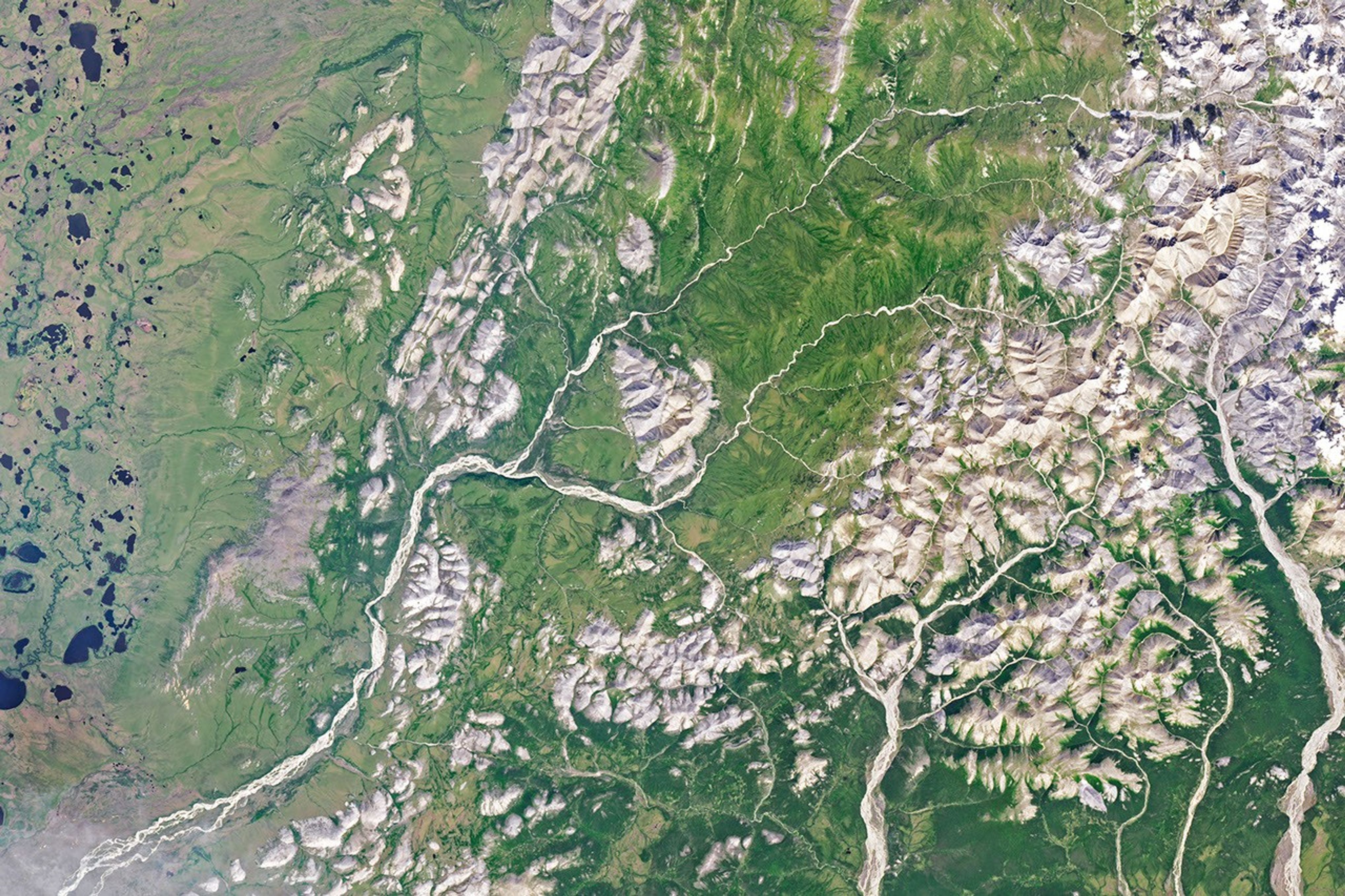A gently curving river runs from right to left through green tundra vegetation.
