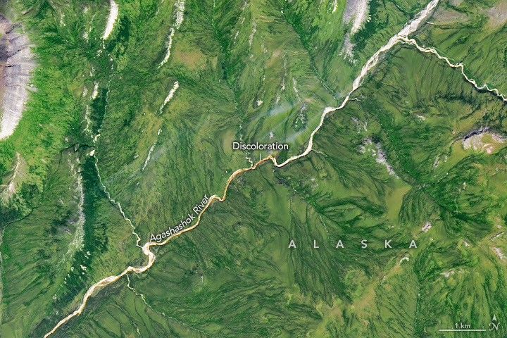 A gently curving river runs from right to left through green tundra vegetation. A segment of the river appears orange.