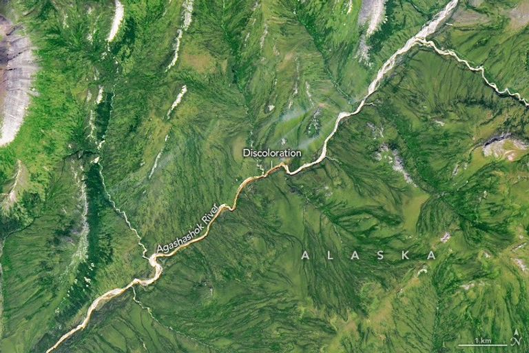 A gently curving river runs from right to left through green tundra vegetation. A segment of the river appears orange.