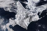 A satellite image shows snow blanketing Hokkaido, Japan, with sea ice swirling just north of the island.