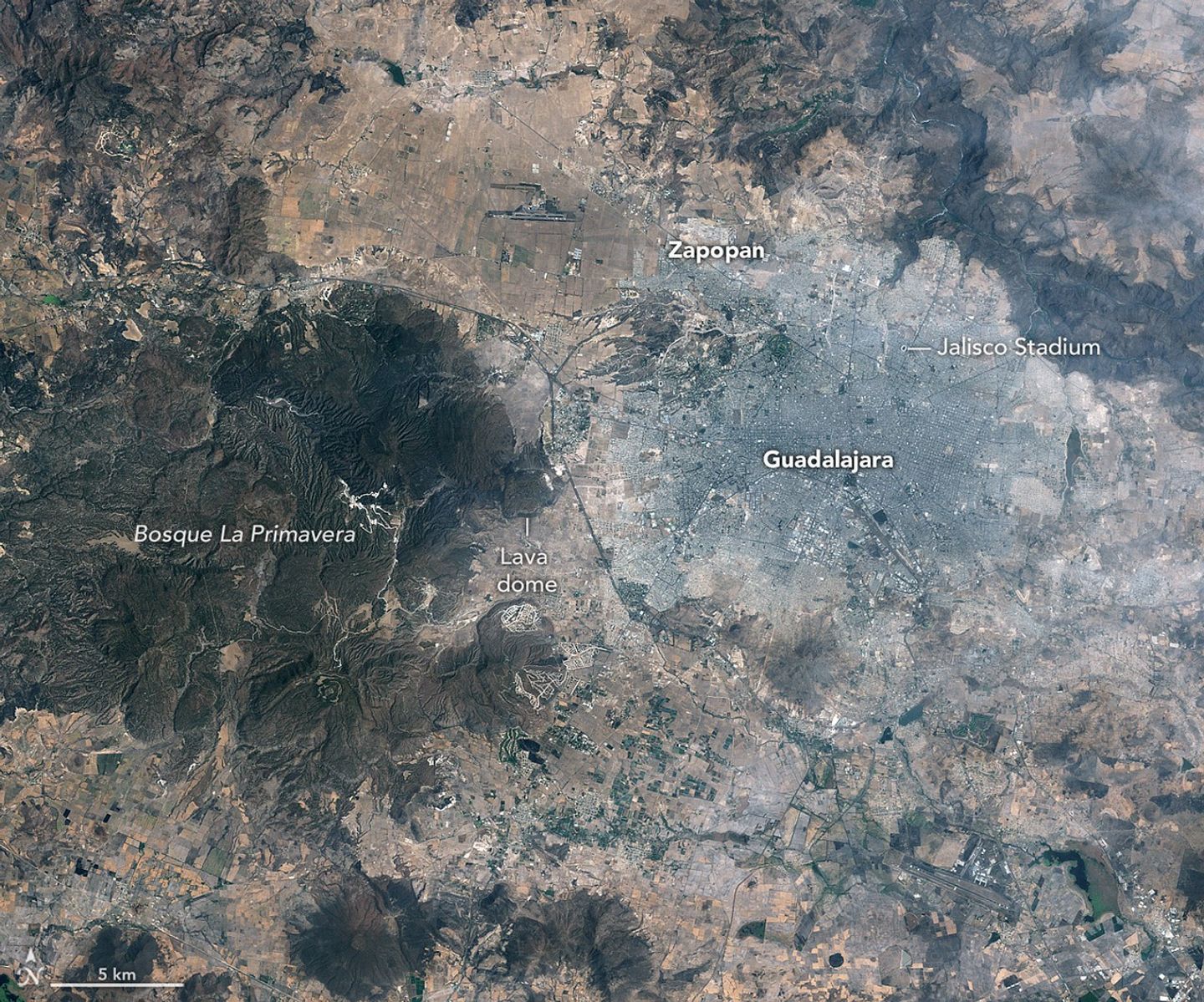 : Images of Guadalajara in 1986 (left) and 2026 (right) shows the city expanding westward into an area that had been mostly farmland. Guadalajara Stadium appears as a small circular feature on the left side of the 2026 image.