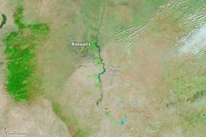 an image of empty green tan land with a river in the center that is blue-green in color