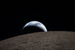 La Tierra se pone sobre el horizonte del lado lejano de la Luna, salpicada de cráteres.