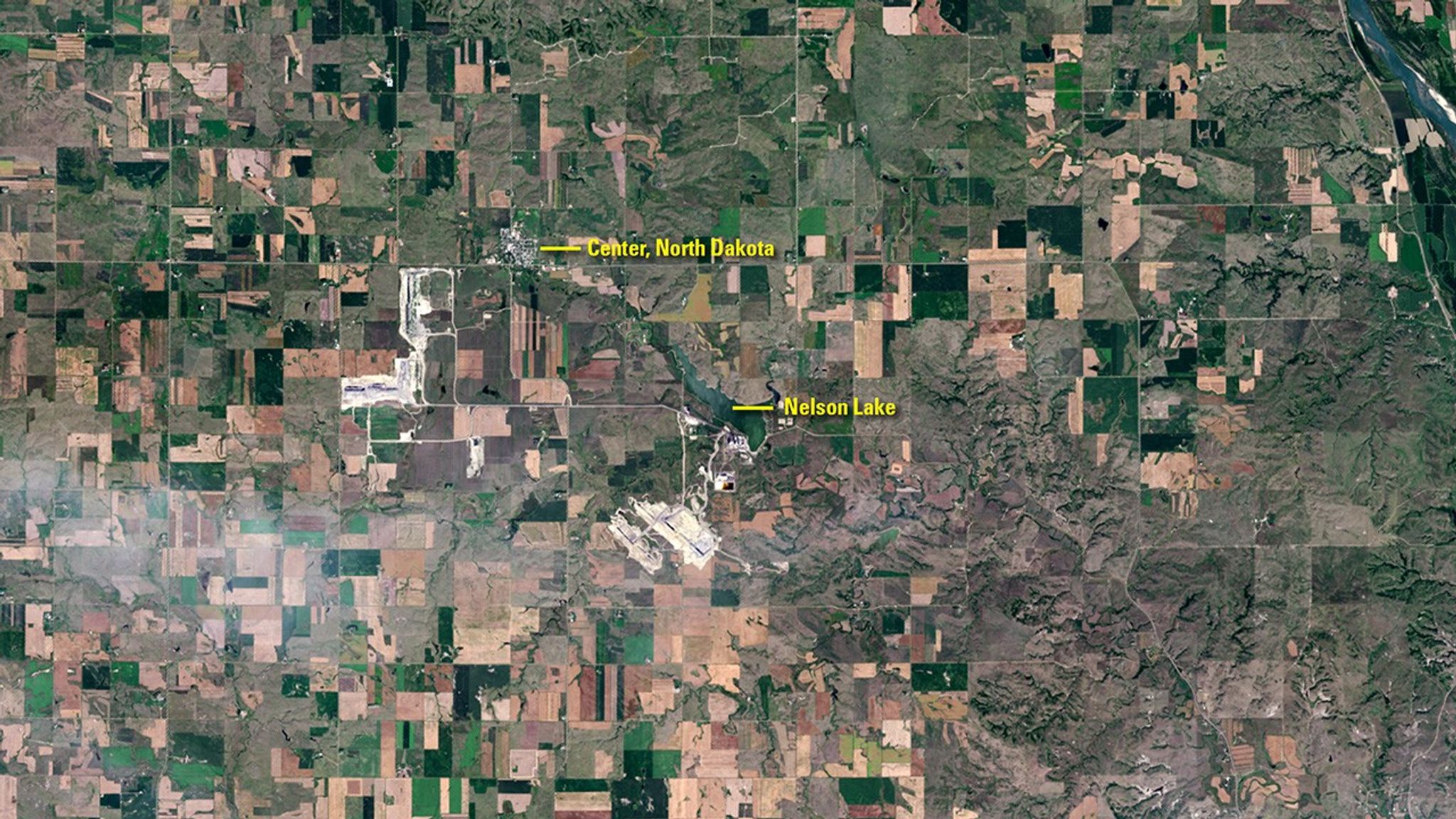 Mining has been part of Center, North Dakota’s history for over a century. The Landsat 5 image from August 1984 (left) shows significant surface mining of lignite coal just to the southeast of town, during a summer when drought had browned the countryside. Thirty-two years later, mining activity moved to the southwest of Center. An additional mining operation also began near the Milton R. Young Power Plant just southwest of Nelson Lake, where lignite is used to heat water and create steam to drive electricity-producing turbines. The North Dakota Geological Survey estimates that western North Dakota contains about 1.3 trillion tons of lignite, and that 25 billion tons are recoverable—enough to last more than 800 years at the current production rate of 30 million tons per year. Left image taken by the Landsat 5 satellite. Right image taken by Landsat 8. Source: U.S. Geological Survey (USGS) Landsat Missions Gallery: “Landsat Monitors Mining at Center of North America Near Town of Center”; U.S. Department of the Interior / USGS and NASA.
