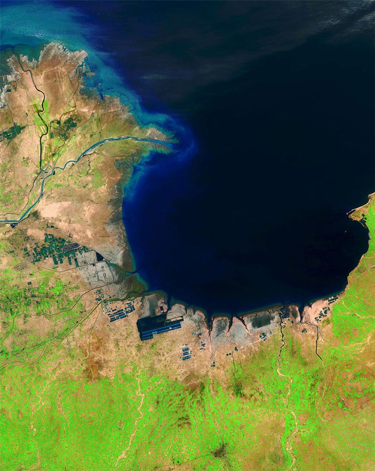 China's Huang He (Yellow) River is the most sediment-filled river on Earth. Each year, it transports millions of tons of soil from a plateau it crosses to a delta it has built in the Bohai Sea. These images show the delta's growth from 1985 to 2014. The latter image also shows another change: ponds that hold shrimp and other seafood (seen here as dark geometric shapes along the coastline) were built on what were once tidal flats.   Images taken by the Thematic Mapper onboard Landsat 5 and the Operational Land Imager onboard Landsat 8. Source: U.S. Geological Survey (USGS) Landsat Missions Gallery "Huang He Delta and Lauzhou Bay," U.S. Department of the Interior / USGS and NASA.