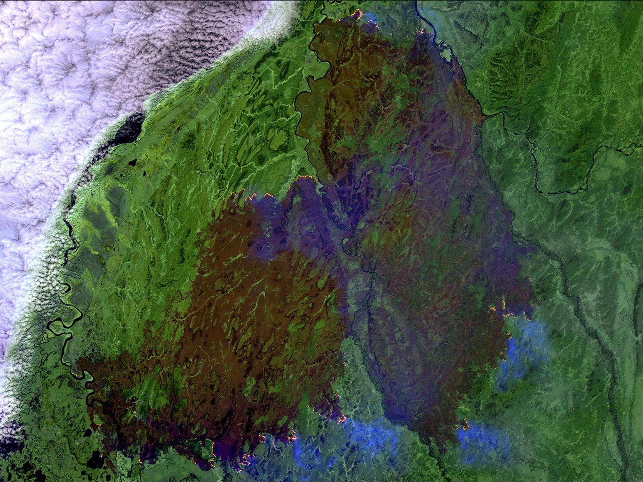 A massive wildfire on the Kamchatka Peninsula in far-eastern Russia has consumed nearly 600,000 acres of boreal forest and tundra since late May 2016. Fires appear orange in the 2016 image and smoke looks light blue. The large, brown area is the burn scar. The Siberian Times reported that smoke from the Russian wildfire was “producing exceptional sunsets” in the western United States and Canada. The newspaper attributed the Kamchatka fire and others this spring in eastern Russia partially to an unusually warm, dry winter and faster than normal snowmelt. Images taken by the Operational Land Imager onboard Landsat 8 and the Enhanced Thematic Mapper Plus onboard Landsat 7. Source: U.S. Geological Survey (USGS) Landsat Missions Gallery; “Large Wildfire Consumes Boreal Forest in Eastern Russia;” U.S. Department of the Interior / USGS and NASA.