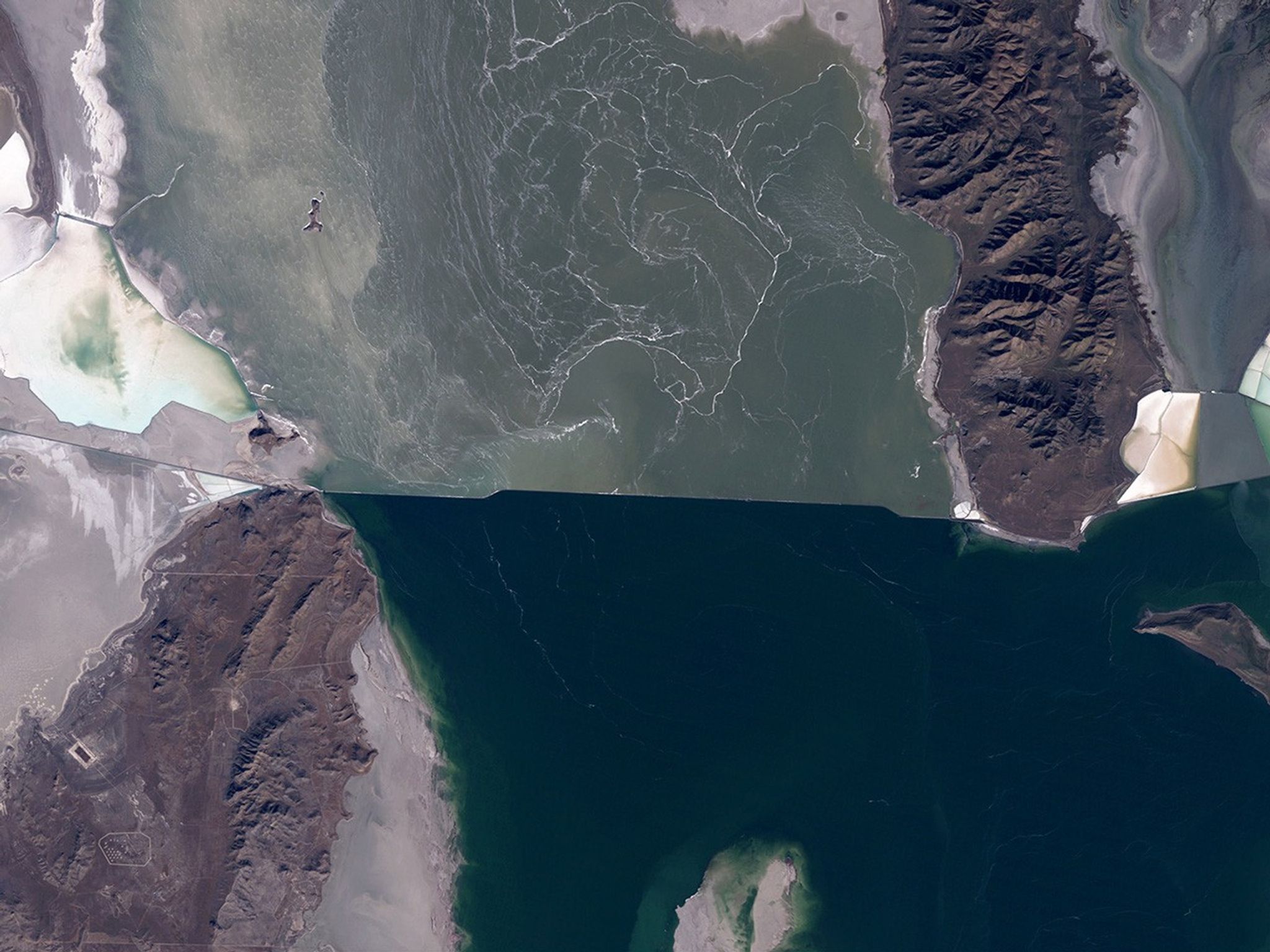 The water level of the north arm of Great Salt Lake, Utah, has reached a record low of 4,191.6 feet because the smaller snowpack of recent years has reduced the spring runoff that feeds the lake. The south arm’s water has dropped below the level where it could cross the breach that separates the arms. Water from the north arm is pumped to evaporation ponds, seen on the right side of these images, from which salt, potassium and other minerals are extracted. Also see this USGS article. Images taken by the Thematic Mapper sensor onboard Landsat 5 and the Operational Land Imager onboard Landsat 8. Source: Landsat Missions Gallery “Great Salt Lake North Arm Reaches Record Low.” U.S. Department of the Interior / USGS and NASA; and USGS Newsroom.