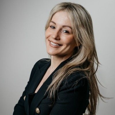 Argyro Kavvada, with blonde hair, stands sideface looking at the camera.