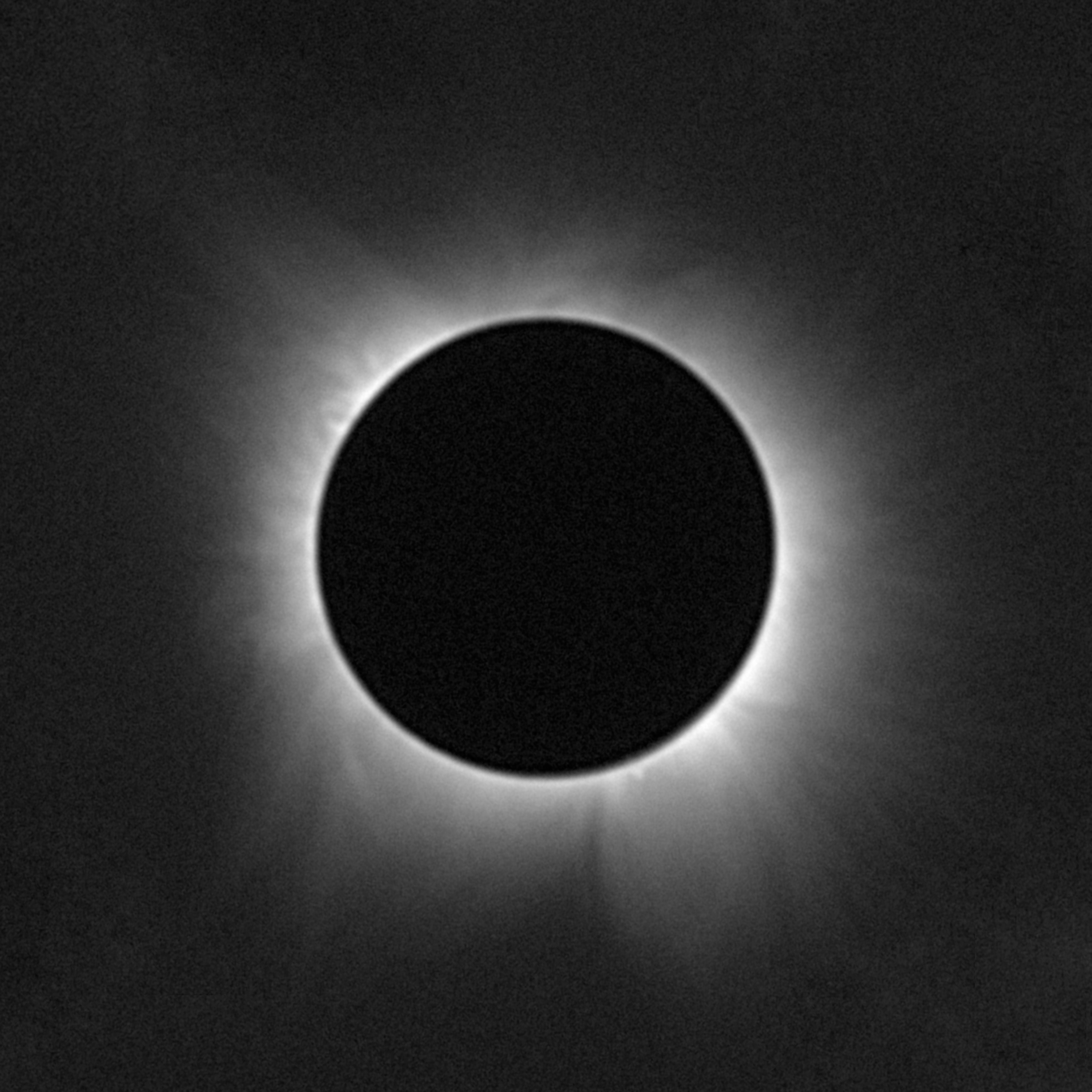 An image of a total solar eclipse shows the Sun's corona, or outer atmosphere as white, wispy tendrils surrounding the Moon's black disk.