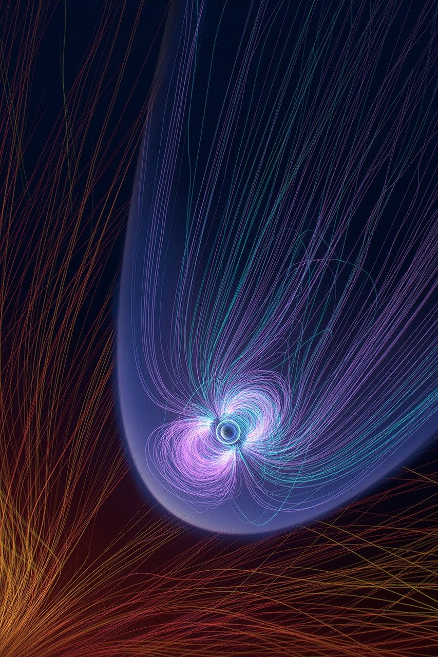 Striking red and orange lines from the bottom left give way around a blueish-purple bubble of geomagnetic lines surrounding Earth.