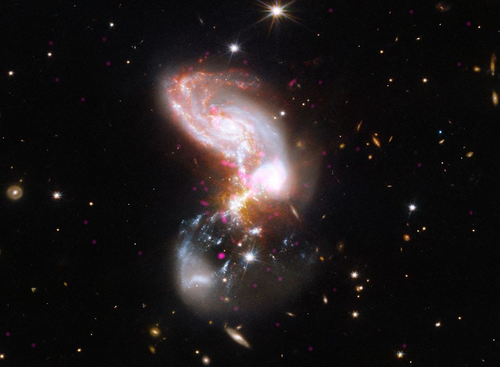 A chaotic, dust-shrouded system of merging galaxies forming stars at a furious rate. Chandra X-ray data (magenta) pinpoint powerful black hole activity and hot gas, while Hubble optical (blue and white) and Webb infrared (red and grey) data illuminate vast stellar nurseries hidden behind interstellar dust. Systems like II Zw 096 show us how powerful galaxy collisions shaped the early universe.