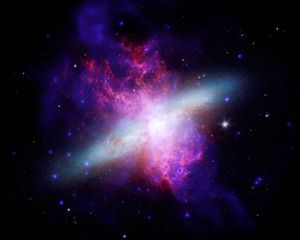 An irregular galaxy undergoing intense star formation because of a gravitational interaction with a neighboring galaxy hundreds of millions of years ago. Chandra X-rays (blue), supplemented by NuSTAR data, show towering superwinds of million-degree gas blowing thousands of light-years out of the galactic disk, with Hubble optical light (yellow, orange and white) showing the galaxy shape, and Webb and Spitzer detailing infrared dust emission (red). M82 was nicknamed the Cigar Galaxy mostly because of its edge-on angle to Earth, which makes its central disk look like an elongated, cigar-shaped oval with small optical telescopes. The galaxy illustrates how violent galactic "exhaust systems" can regulate a galaxy's growth by venting gas outwards.