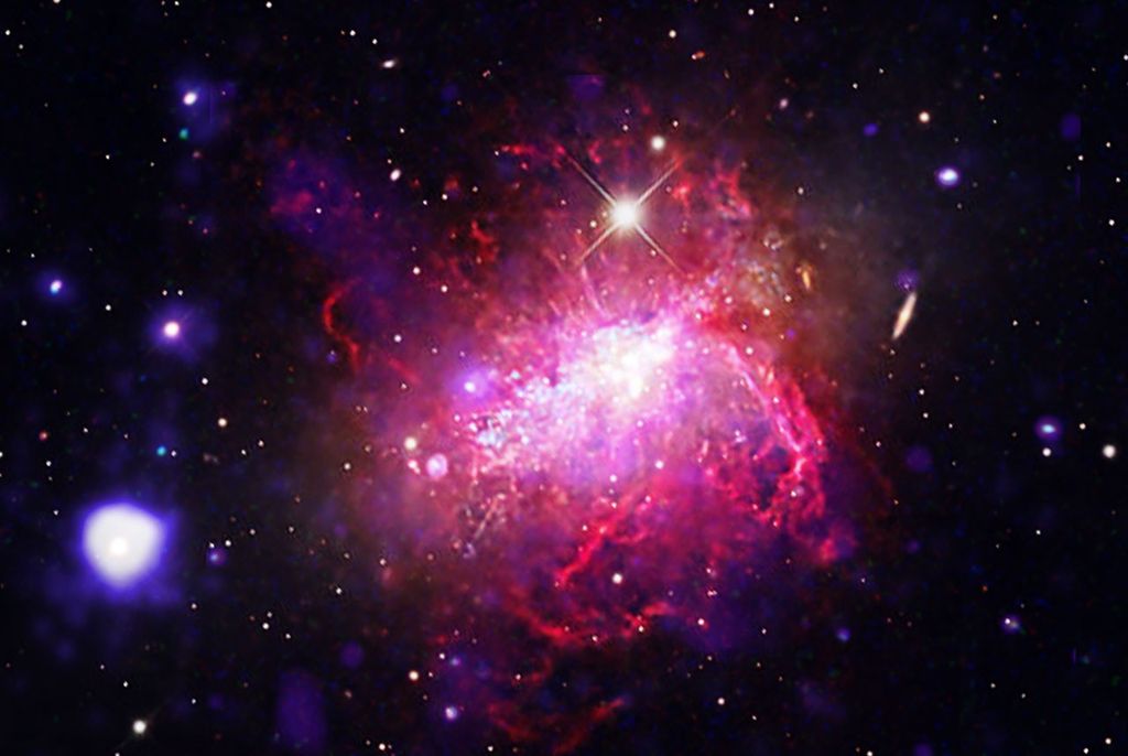 A compact dwarf irregular galaxy undergoing a violent, compact burst of star formation. Chandra and XMM-Newton observations (blue and purple) reveal massive bubbles of million-degree gas inflated by stellar winds, set against a backdrop of optical light (magenta, orange and white) imaged by Adam Block. Dwarf starburst galaxies can serve as local laboratories for studying the conditions of the early universe, where small, primitive galaxies formed stars at frantic rates.