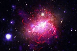 A compact dwarf irregular galaxy undergoing a violent, compact burst of star formation. Chandra and XMM-Newton observations (blue and purple) reveal massive bubbles of million-degree gas inflated by stellar winds, set against a backdrop of optical light (magenta, orange and white) imaged by Adam Block. Dwarf starburst galaxies can serve as local laboratories for studying the conditions of the early universe, where small, primitive galaxies formed stars at frantic rates.