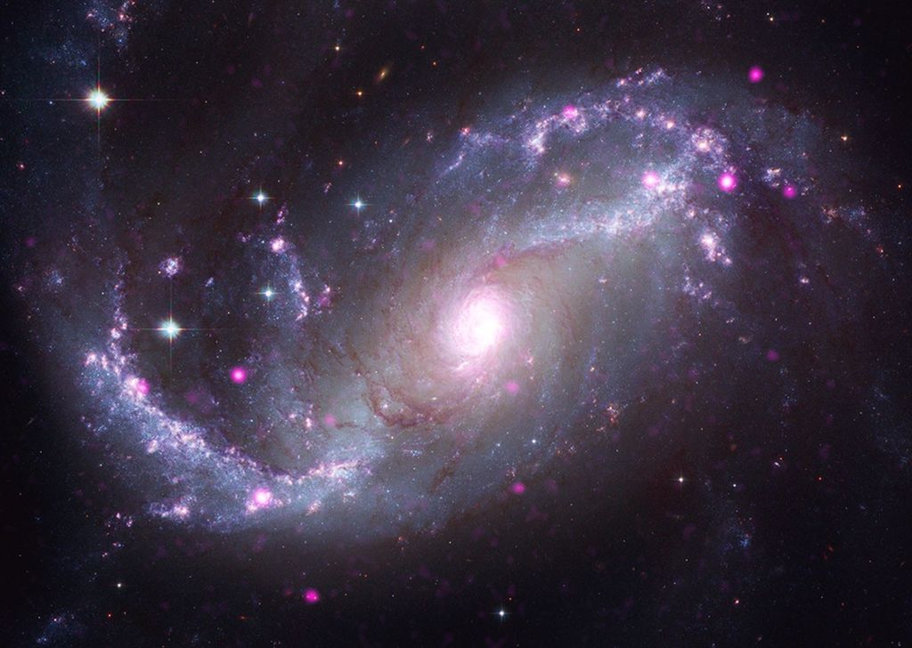 A barred spiral galaxy featuring a prominent central bar or bridge of stars that channels gas toward its core. Chandra X-rays (purple) highlight growing black holes along the bar and core, merged with Hubble optical light (white, yellow and soft blue) and JWST infrared dust filaments (red). Studying barred spirals in action can help reveal how gas in our own Milky Way, which is also a barred spiral, feeds its central black hole and forms new stars.
