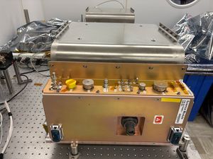 Add image and text: Heat Exchanger Module 1B consisting of two electronics assemblies sandwiching a heat exchanger plate with a hose that connects to CAL’s and ISS’s water cooling system.
