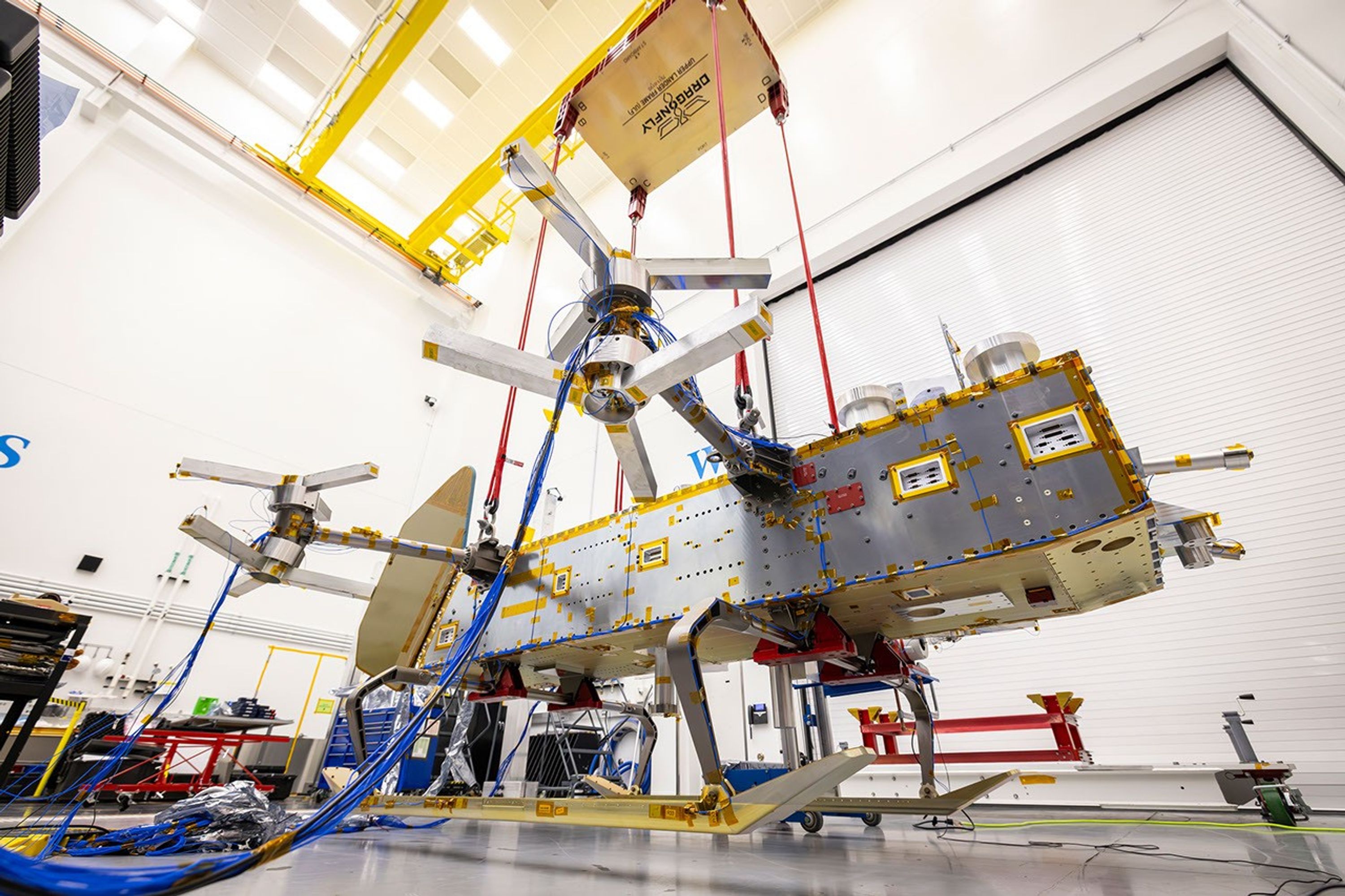 Dragonfly’s lander frame assembly hangs from red straps during a ground vibration test at APL.