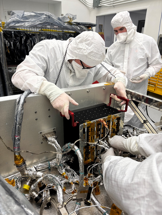 Nella camera bianca dell'APL, Emory Toomey (a sinistra) e Hunter Reeling integrano il modello ingegneristico dell'IEM di Dragonfly, che contiene l'avionica principale del veicolo, con il cablaggio elettrico del lander. Credits: NASA/Johns Hopkins APL