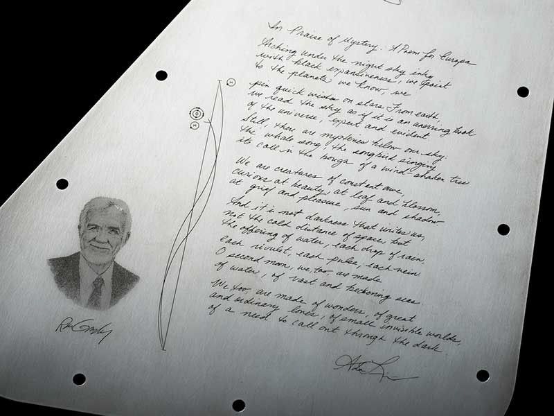 This is a close-up view of the poem on the Europa Clipper vault plate’s inward-facing side. It shows a handwritten poem in elegant script, and an engraved portrait of man to the left of the poem.
