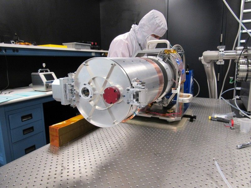 An engineer inspects the test setup of the optical telescope assembly for the Europa Imaging System narrow angle camera.