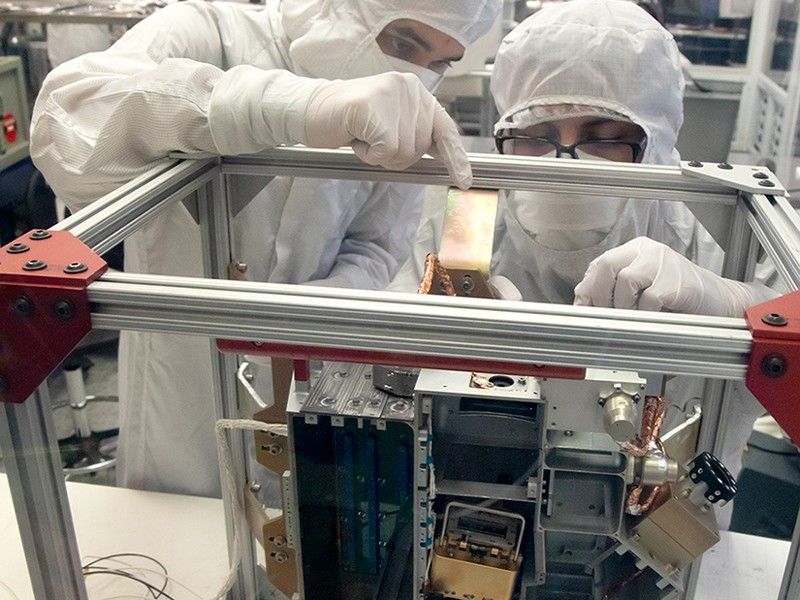 Southwest Research Institute’s Brandon Perez (mechanical engineer; left) and Bryan Esquivel (technician; right) prepare to install electrical boards into Europa Clipper's ultraviolet spectrograph, tipped up to show a top view.