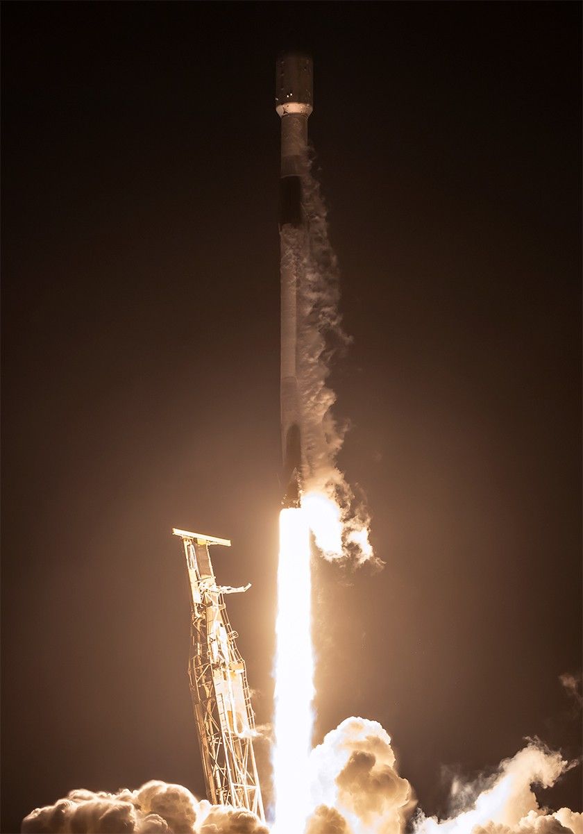 : A rocket lifts off from a launch pad at night, with the scene lit by rocket’s bright trail. Clouds of vapor billow out on the ground and from the rockets upper half.