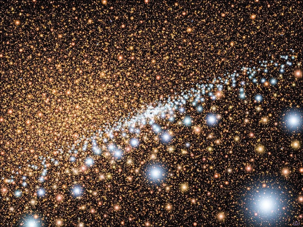 Countless stars appear as glowing spheres that are concentrated more heavily on the left and become more scattered on the right. Most of them are yellow-orange and red-orange, but from the center, a disk of white stars spreads out in a disk across the image and toward the lower right.